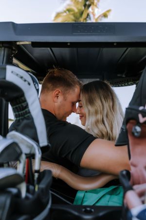 Couple sharing an intimate moment inside a golf cart.