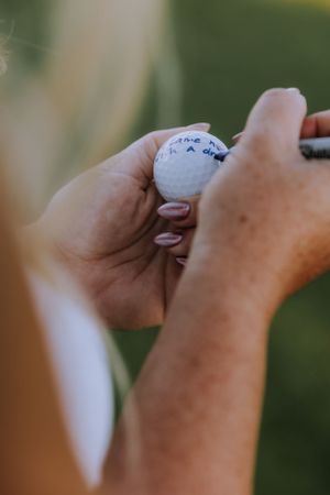 Detailed sequence of hands marking a golf ball outdoors.