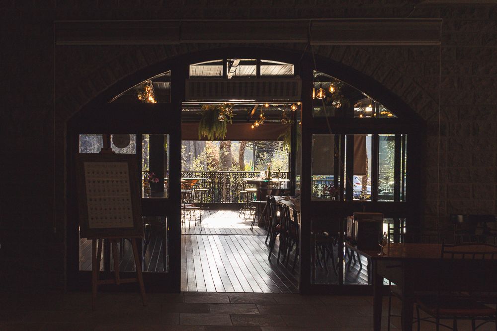 Warmly lit restaurant interior with arched doorway and wooden floor, photographed by Piret Victoria Ribas.