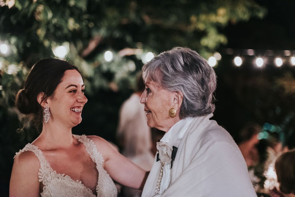 A bride smiles broadly while talking with her new in-laws.