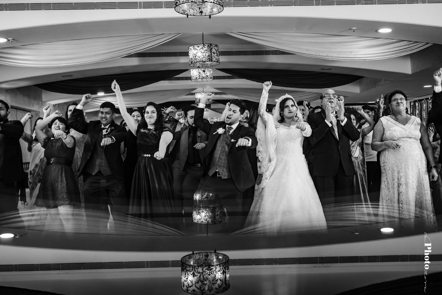 Wedding reception dance floor filled with guests celebrating under draped fabric ceiling decor.