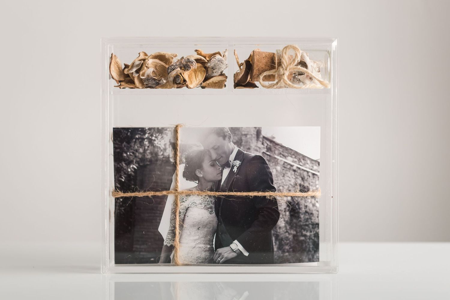 Wedding photos stored in a clear acrylic box with rustic cork decorations.
