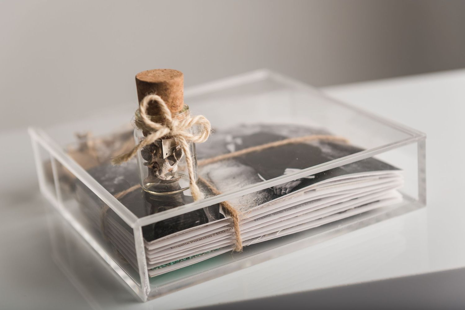 Clear acrylic box containing photographs tied with twine and decorated with cork stoppers.