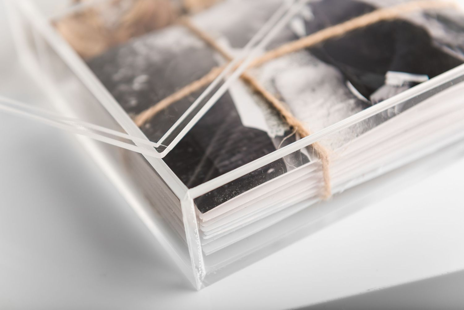 Transparent photo box with wrapped photographs secured by natural twine.