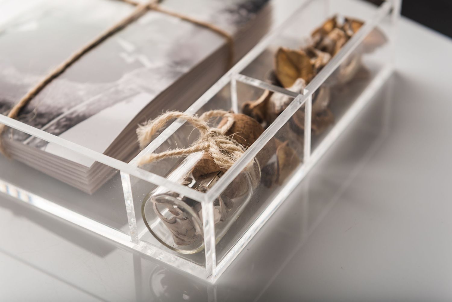 Close-up of photographs stored in a transparent acrylic box with twine wrapping.