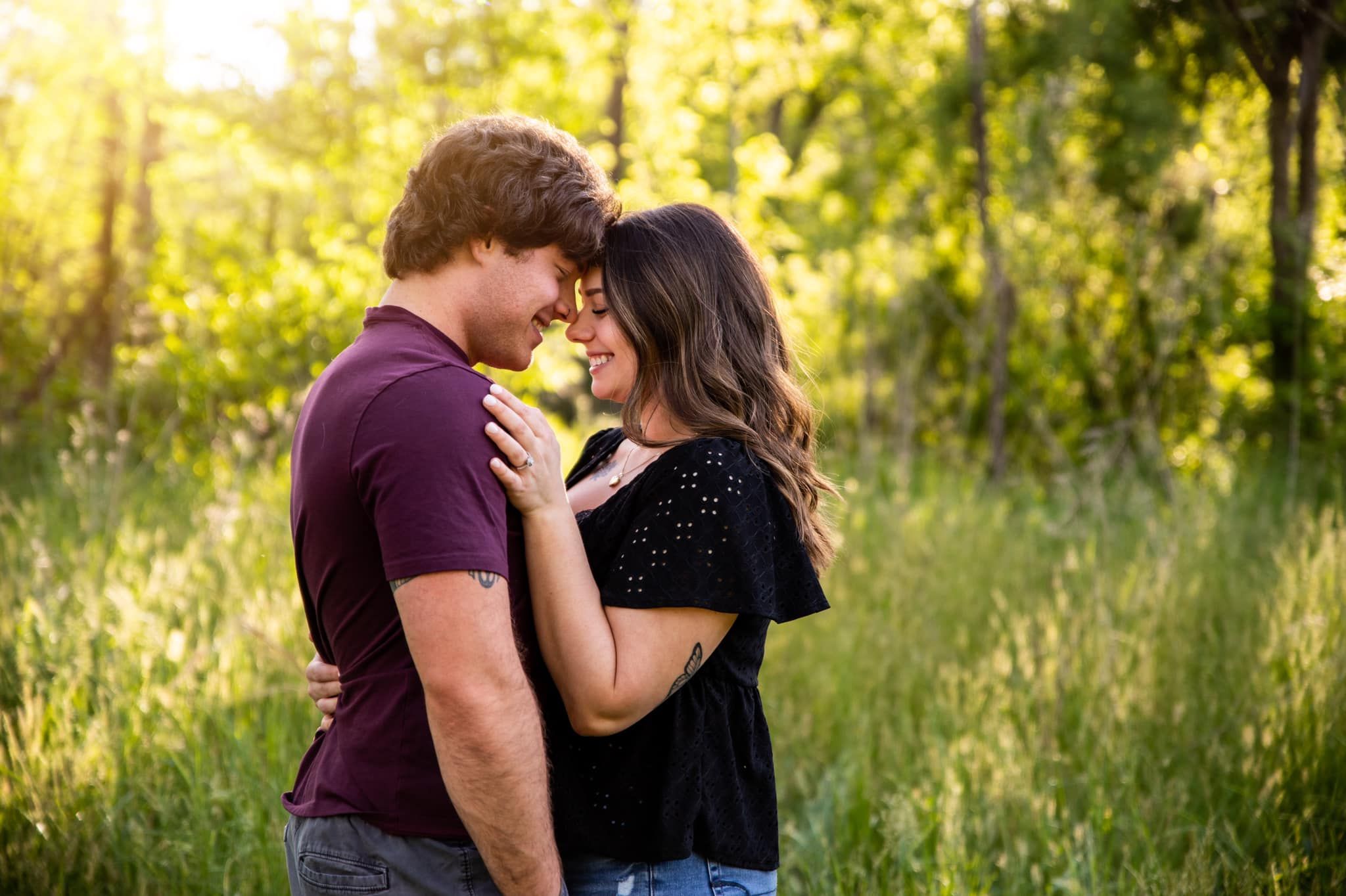 Two people sharing an intimate moment in a sun-drenched field at golden hour.