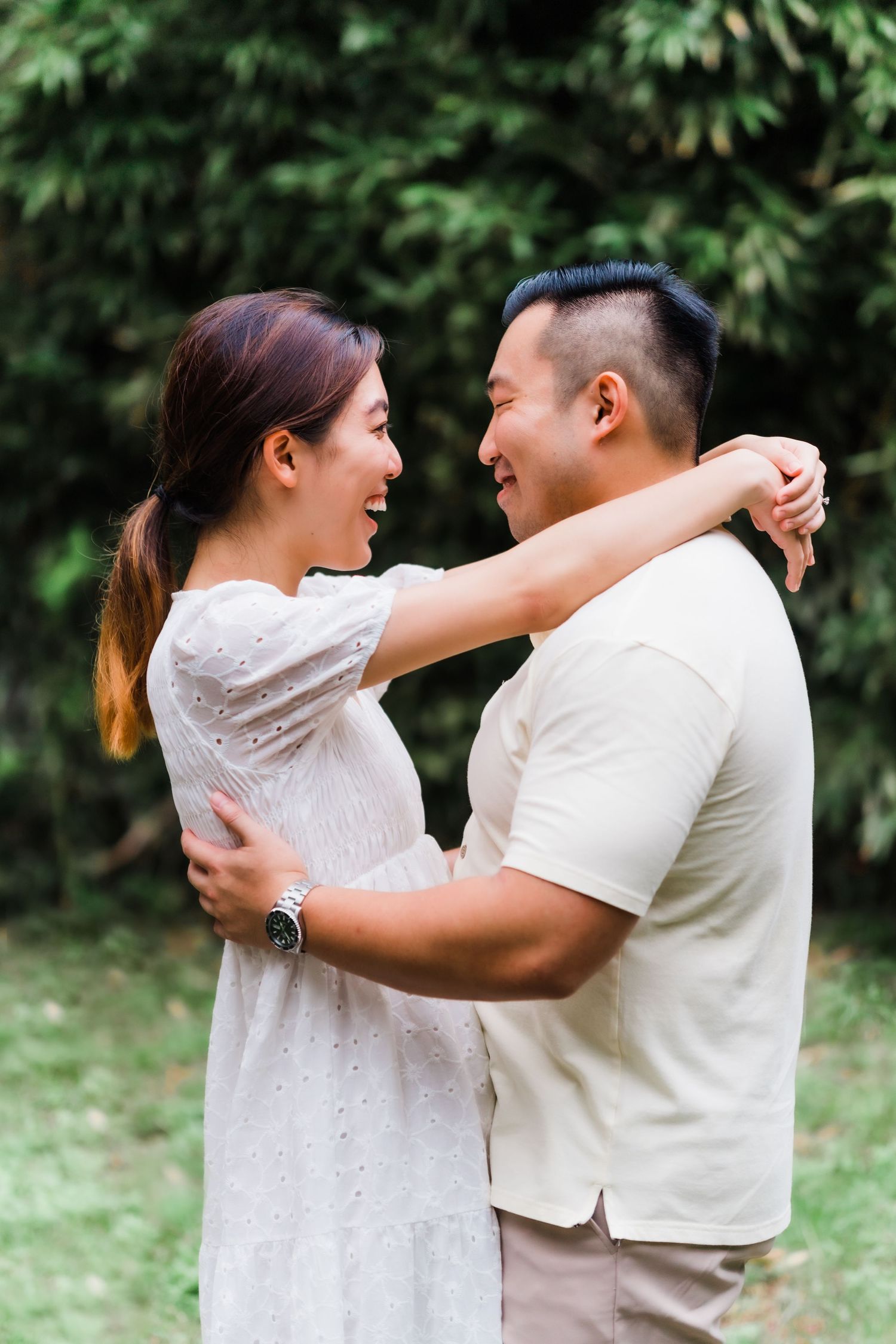A couple embraces while sharing a happy moment in a garden setting.