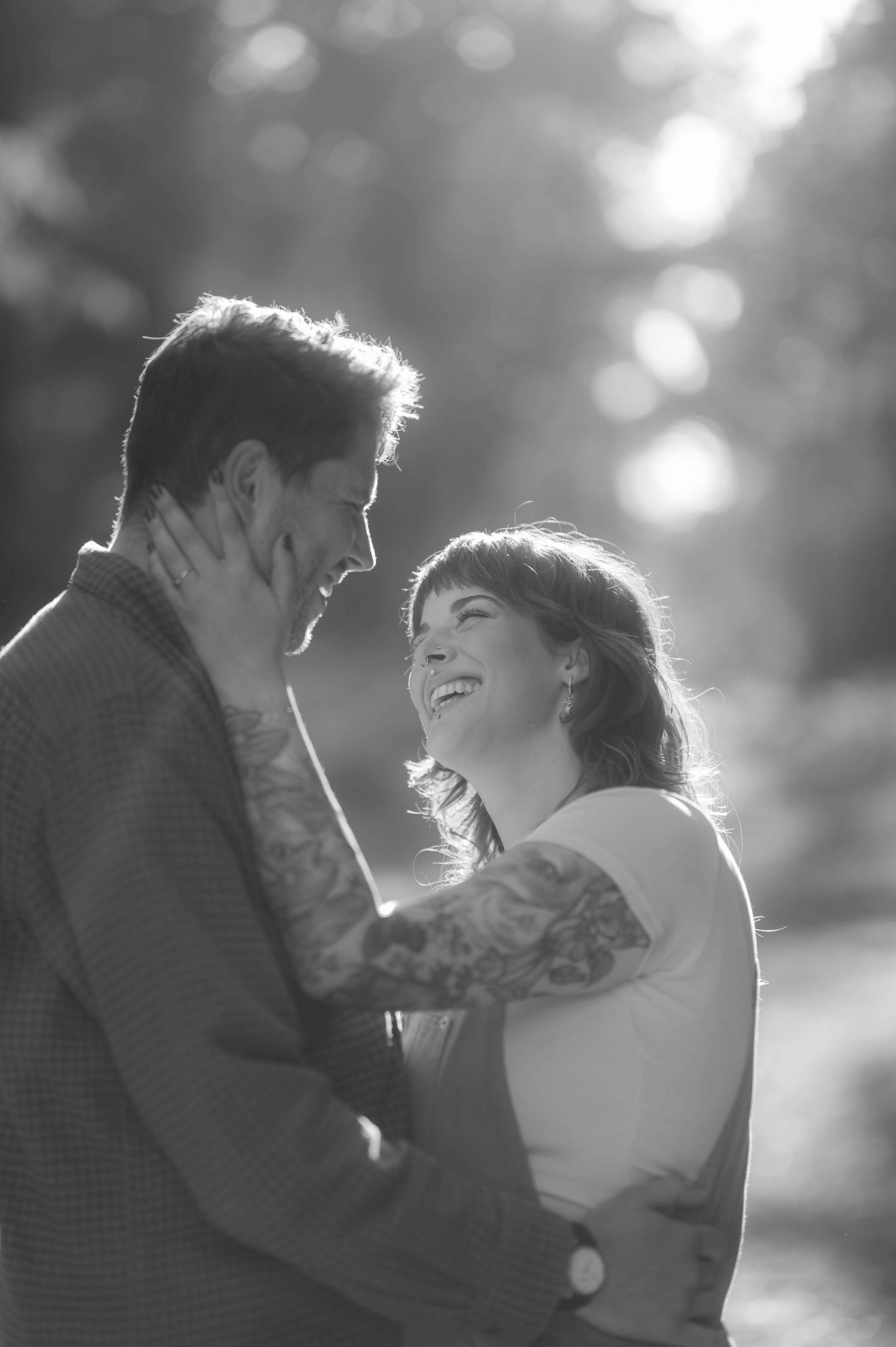 A romantic black and white portrait captures an intimate moment between a couple in soft natural light.