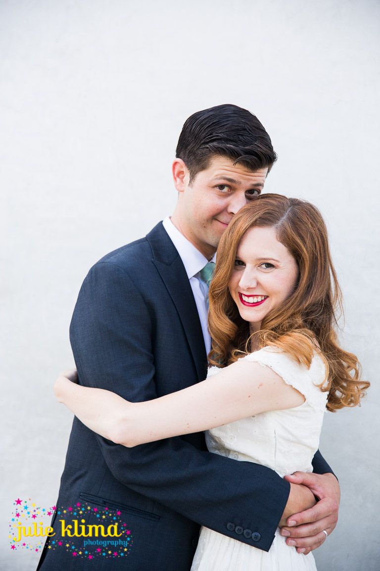 Romantic couple embraces while dancing in formal attire against white backdrop.