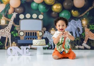 First birthday celebration with safari decorations and happy child sitting on floor.