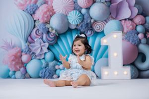 Baby's first birthday photo with pastel balloon decorations and light-up number one.