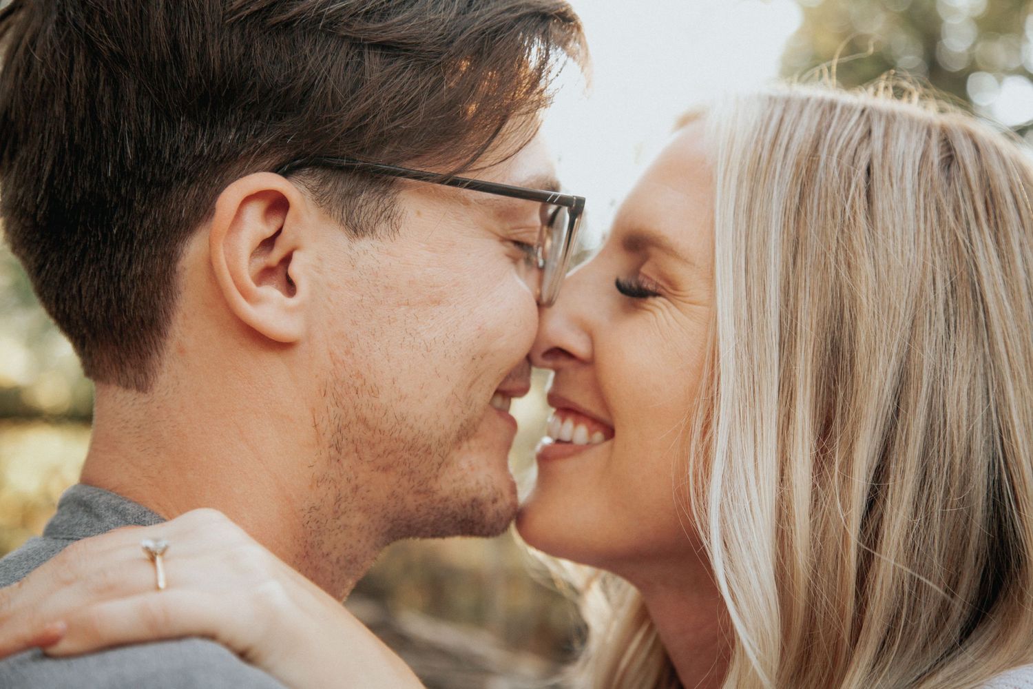 A joyful couple shares a close romantic moment outdoors in warm sunlight.