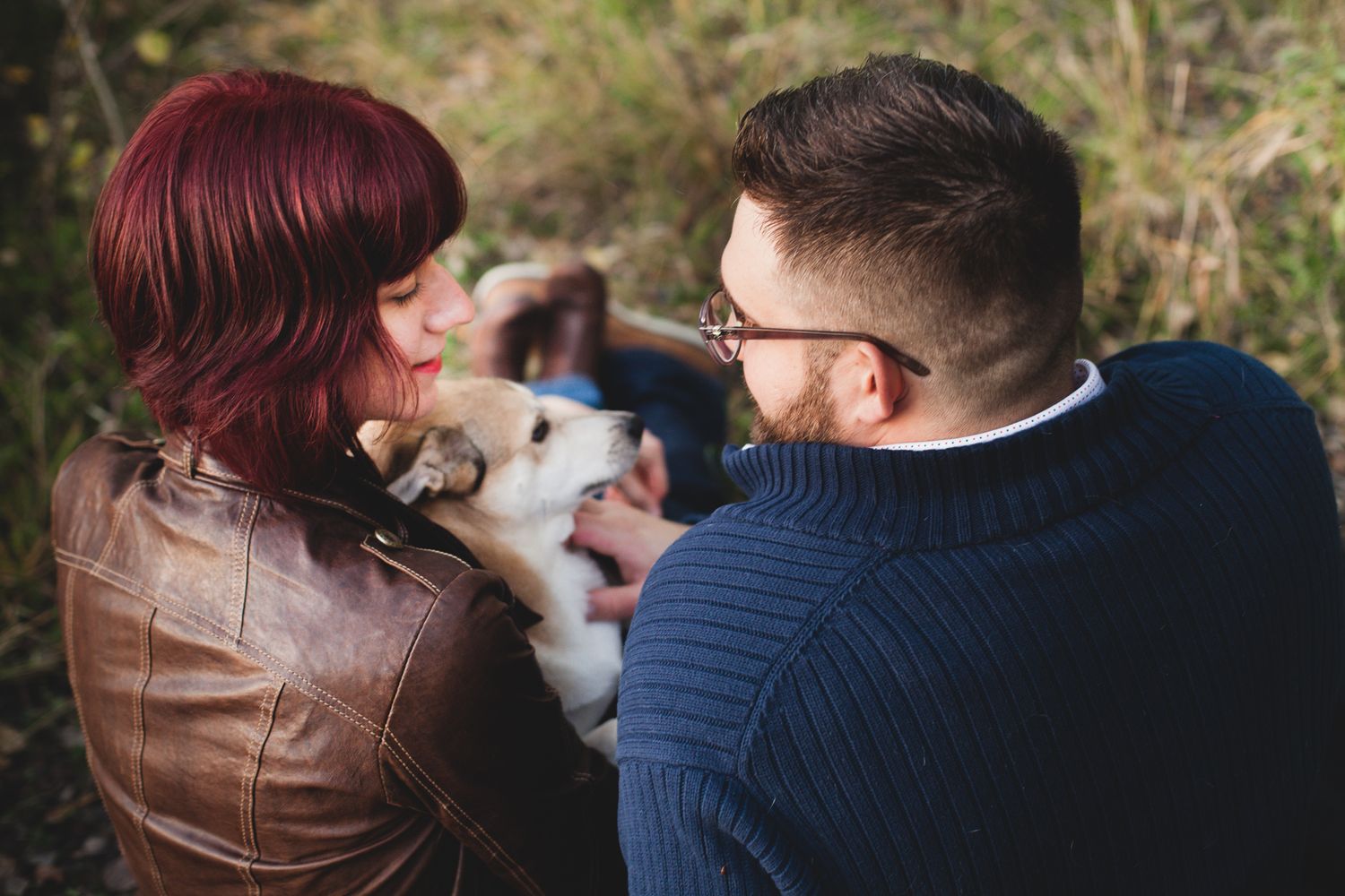 Couple cuddling with their dog outdoors in black and white photo.
