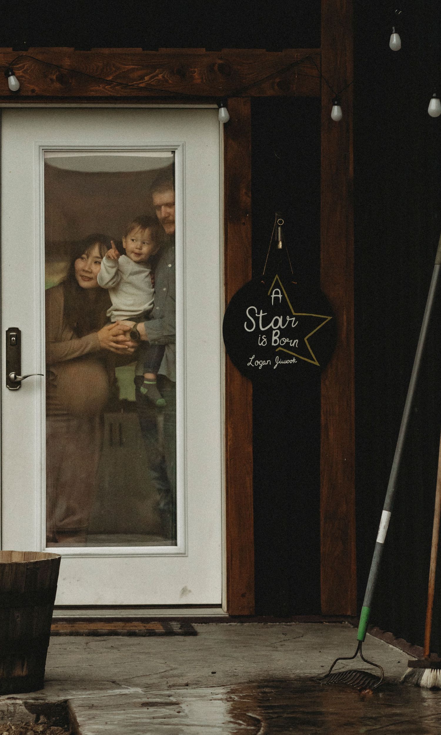 Family peeking through glass door with a decorative star sign hanging beside it.