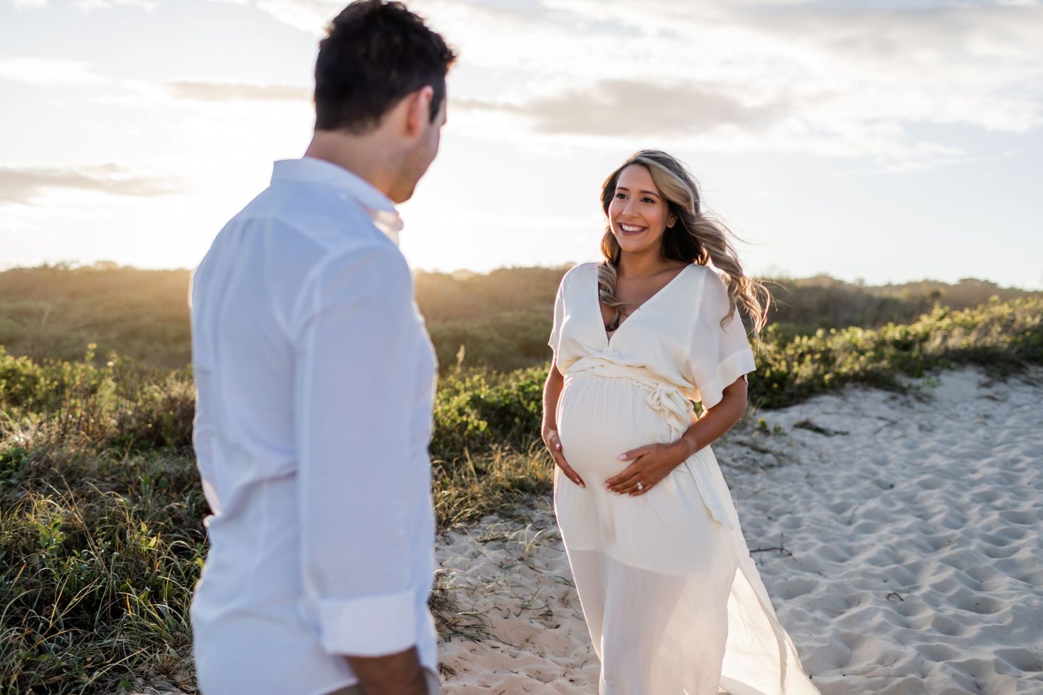 A couple shares candid moments during their beachside maternity photoshoot.