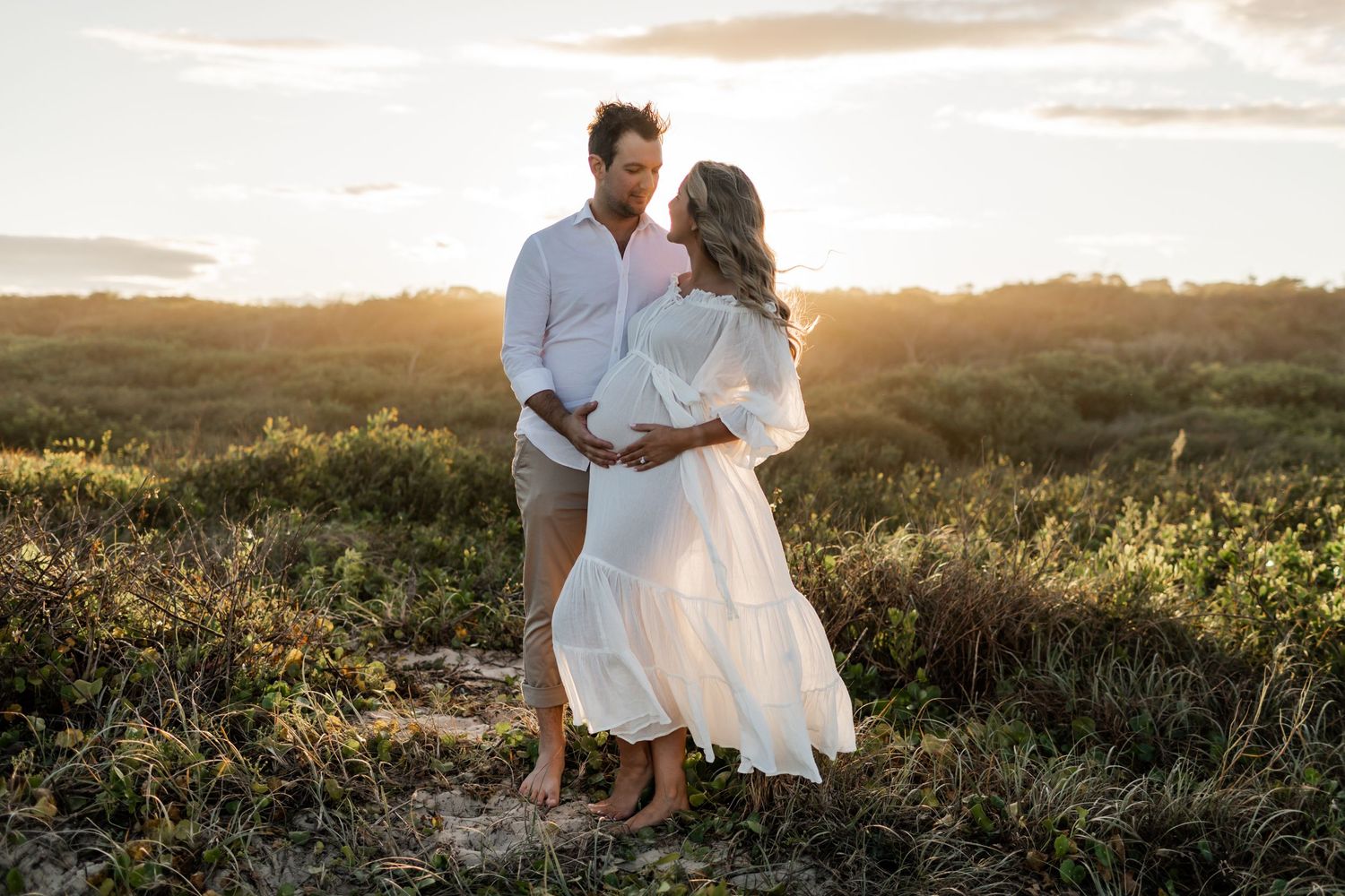 A couple shares a romantic moment during their sunset maternity session.