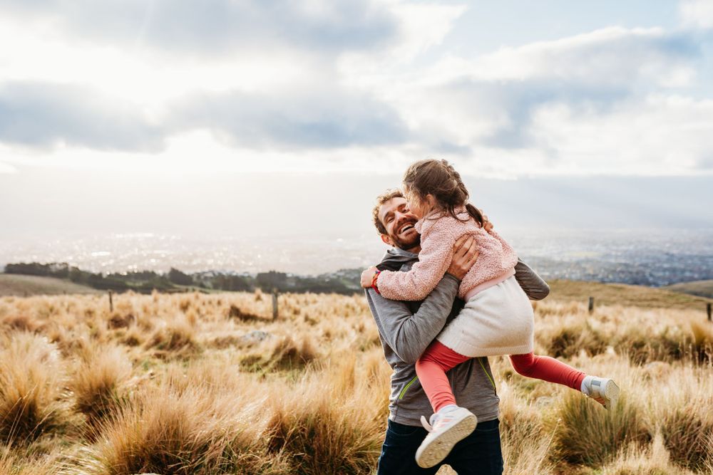 Playful piggyback ride moment captured in scenic grassland landscape.