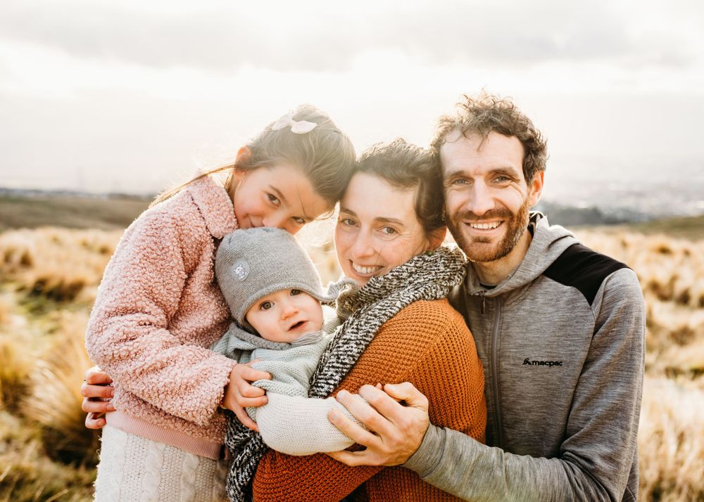 Warm family portrait during golden hour in natural outdoor setting.