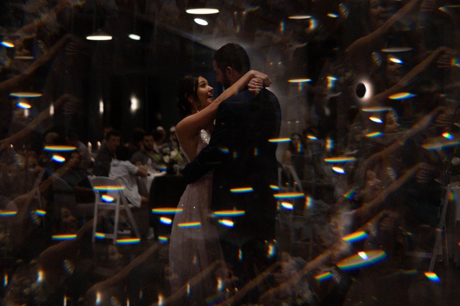 Silhouetted dancing figures with light flares creating a dreamy atmosphere.
