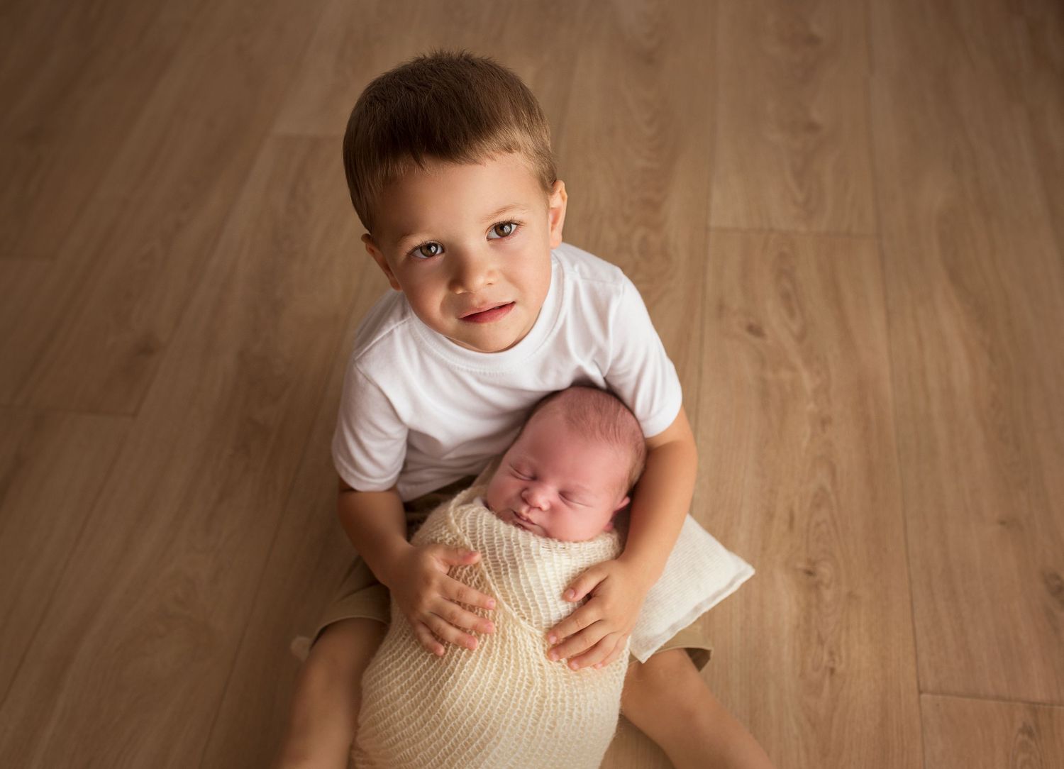 toddler big brother holding newborn