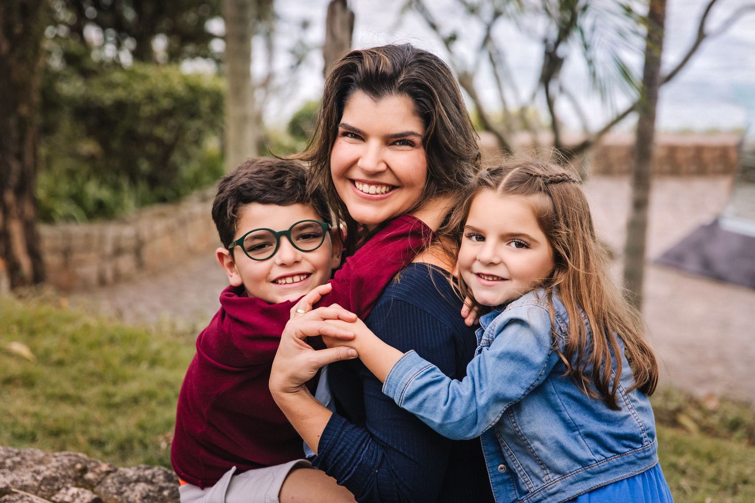 Outdoor family portrait showing warm embrace between three people.