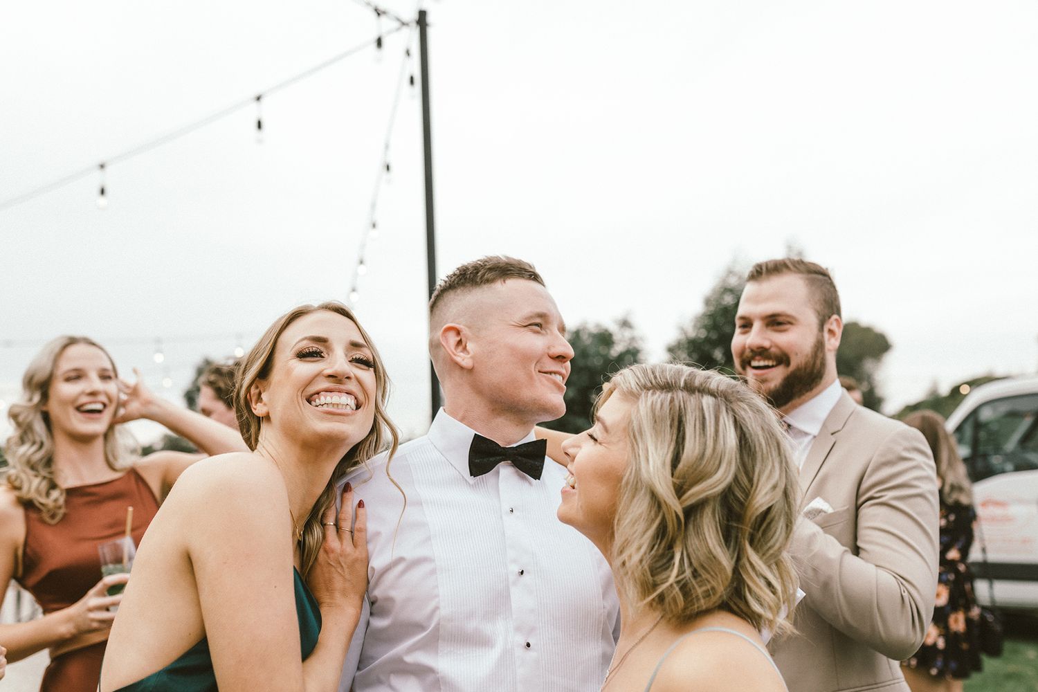 Joyful wedding party sharing laughs during outdoor celebration.