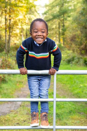 happy small boy climbing a gate