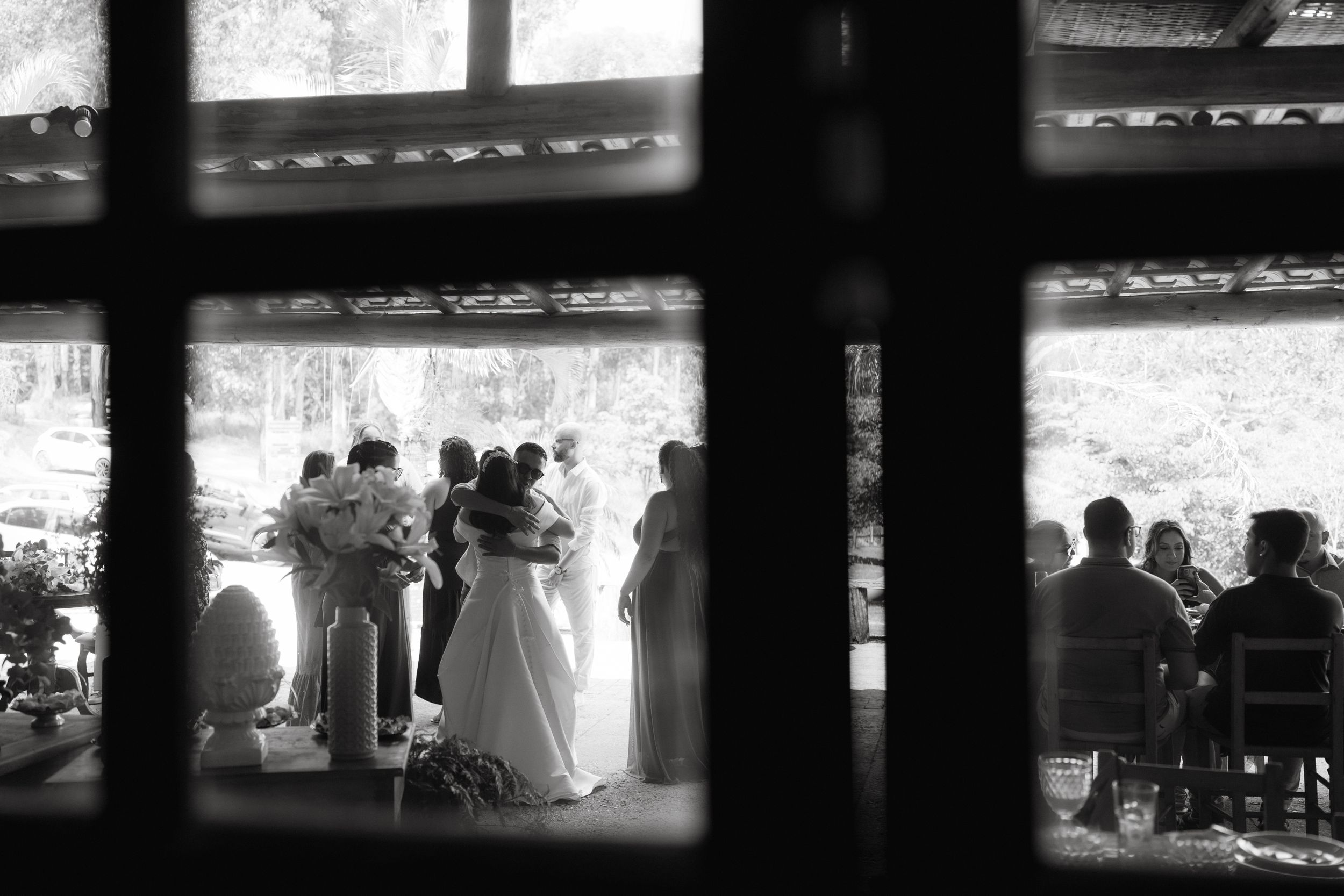 Black and white photo of wedding ceremony viewed through window panes.