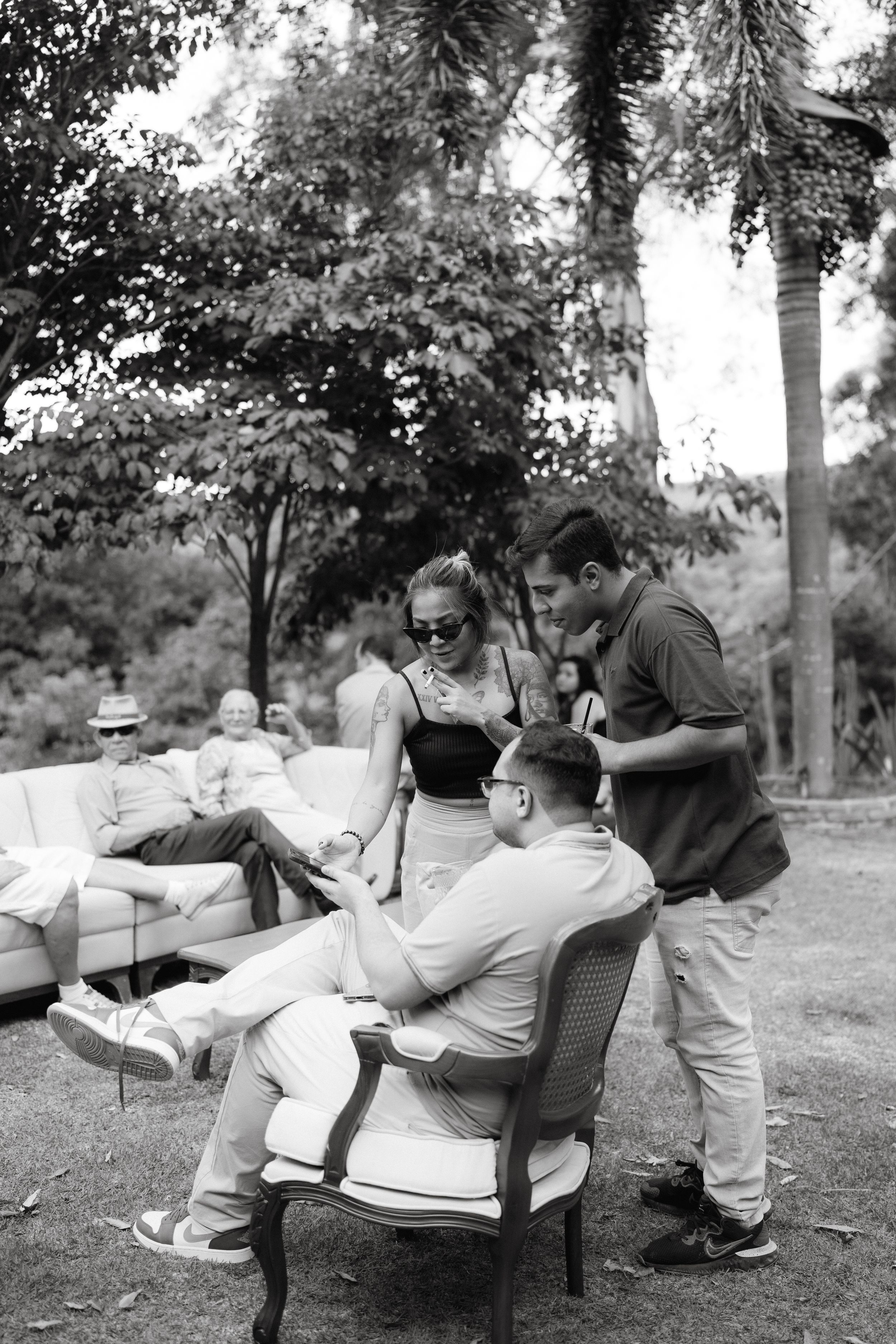 Black and white photo of casual outdoor gathering with vintage furniture.