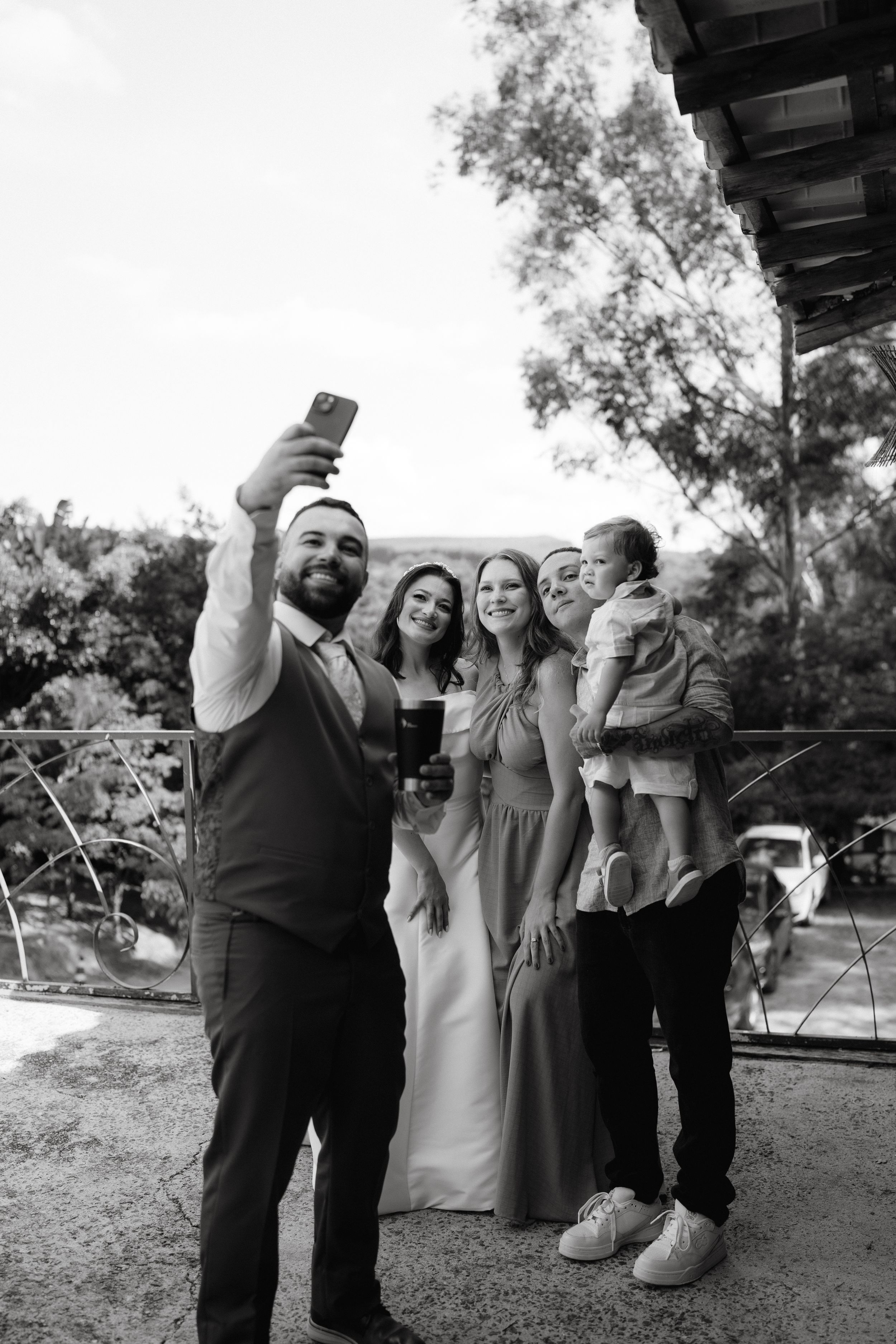 Group takes selfie during wedding reception in black and white photography.