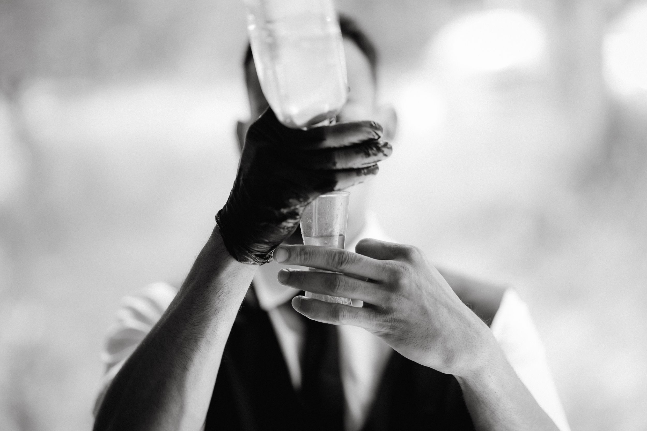Black and white close-up of hands holding champagne glasses in celebration.