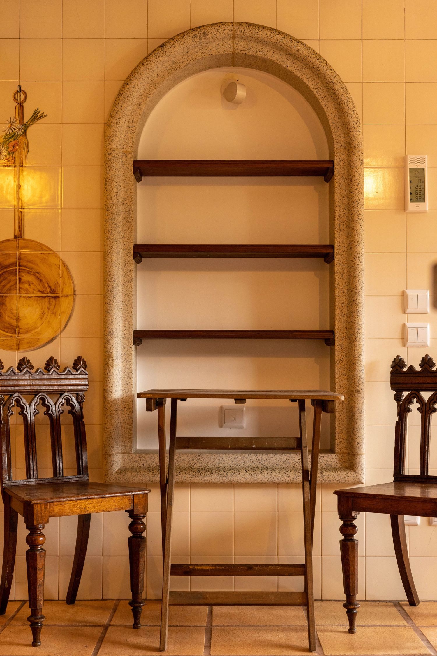 Gothic-style wooden chairs and shelves in arched alcove with vintage decorative elements.