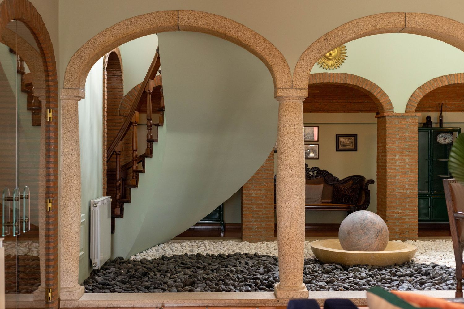 Interior archway with black stones and curved architectural details leading to staircase.