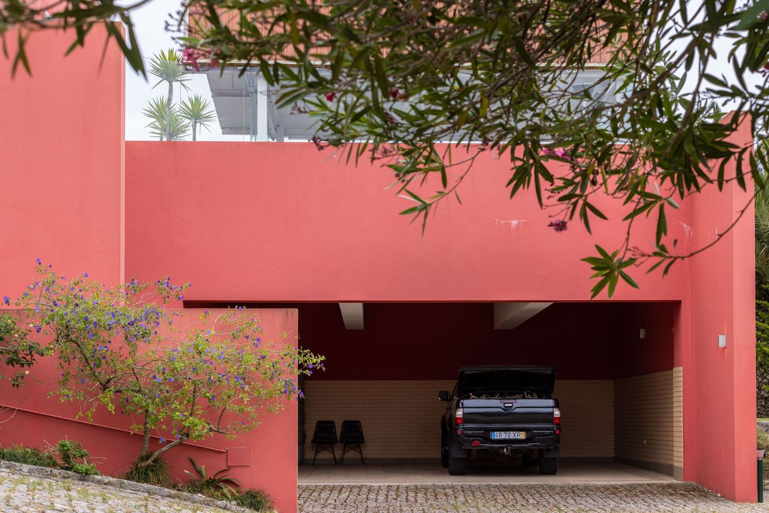 Modern coral-colored house exterior with covered carport and landscaping.