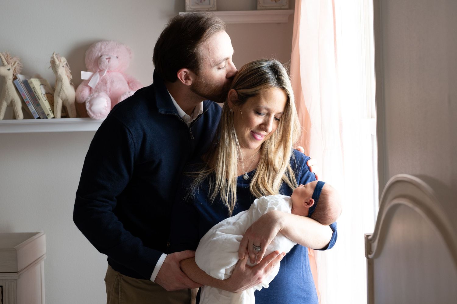 father kisses his wife on the head during a newborn lifestyle session in houston texas