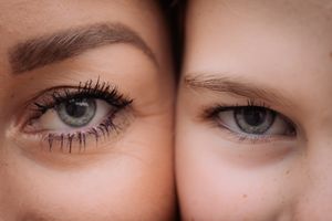 Extreme close-up of two pairs of blue eyes showing contrasting makeup and natural looks.