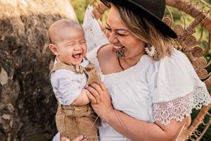 Joyful laughter shared between two people in a rustic outdoor setting with stone wall.