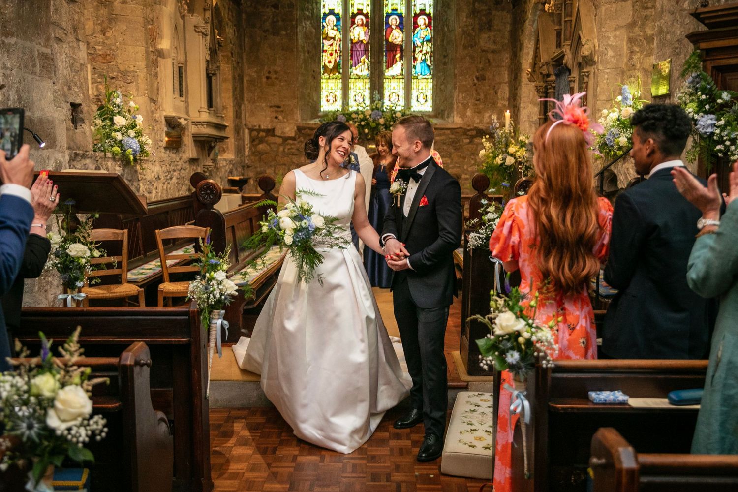 Wedding ceremony in a beautiful historic church with stained glass windows and floral decorations.