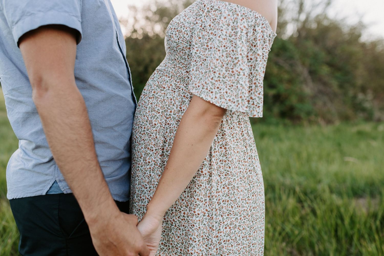 Intimate couple's portrait session in a grassy field during golden hour.