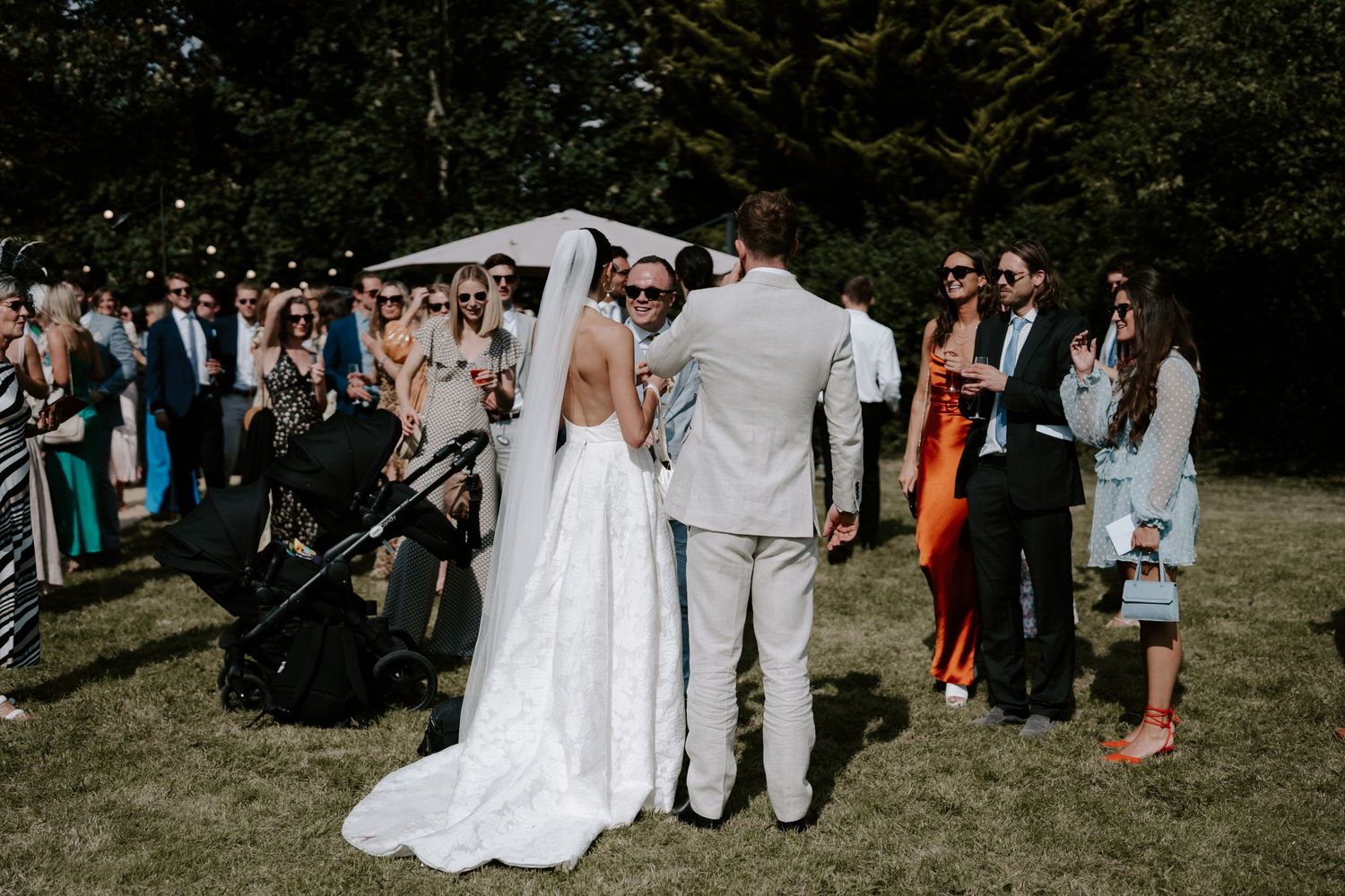 Bride and groom surrounded by wedding guests outside marquee in islip, oxfordshire