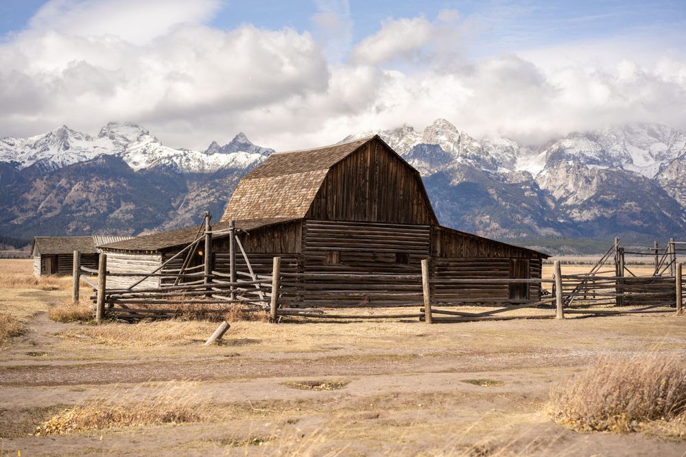 Historic wooden barn with mountain backdrop in Grand Teton National Park.