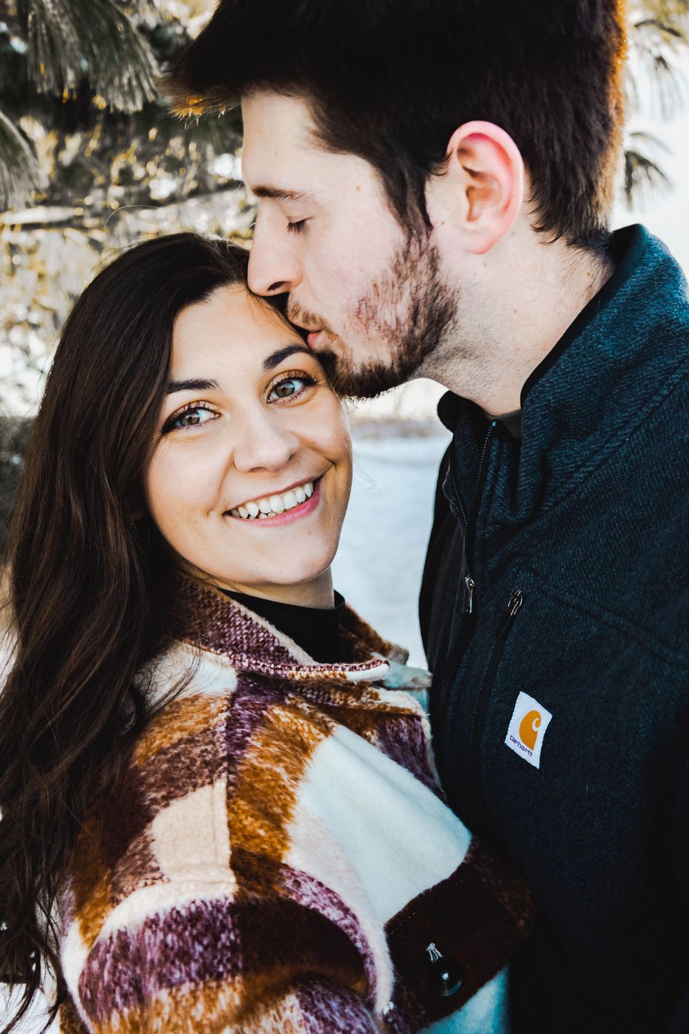 Close-up winter portrait of a couple sharing an intimate moment wearing warm clothing.