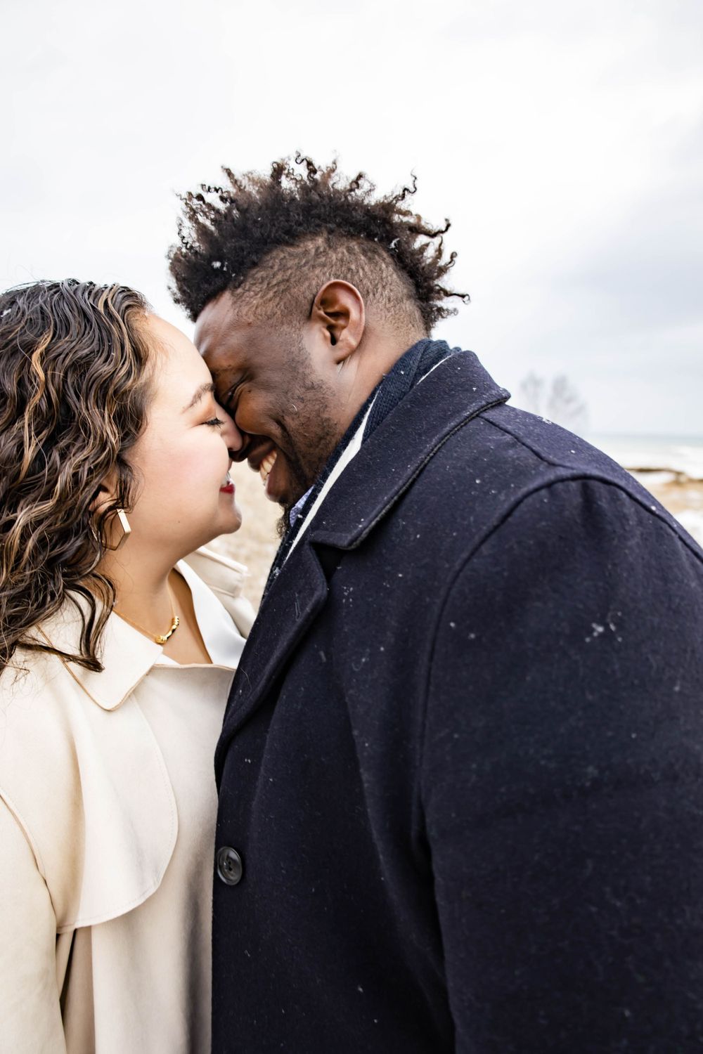 An intimate close-up of a couple sharing a tender moment against a cloudy sky background.