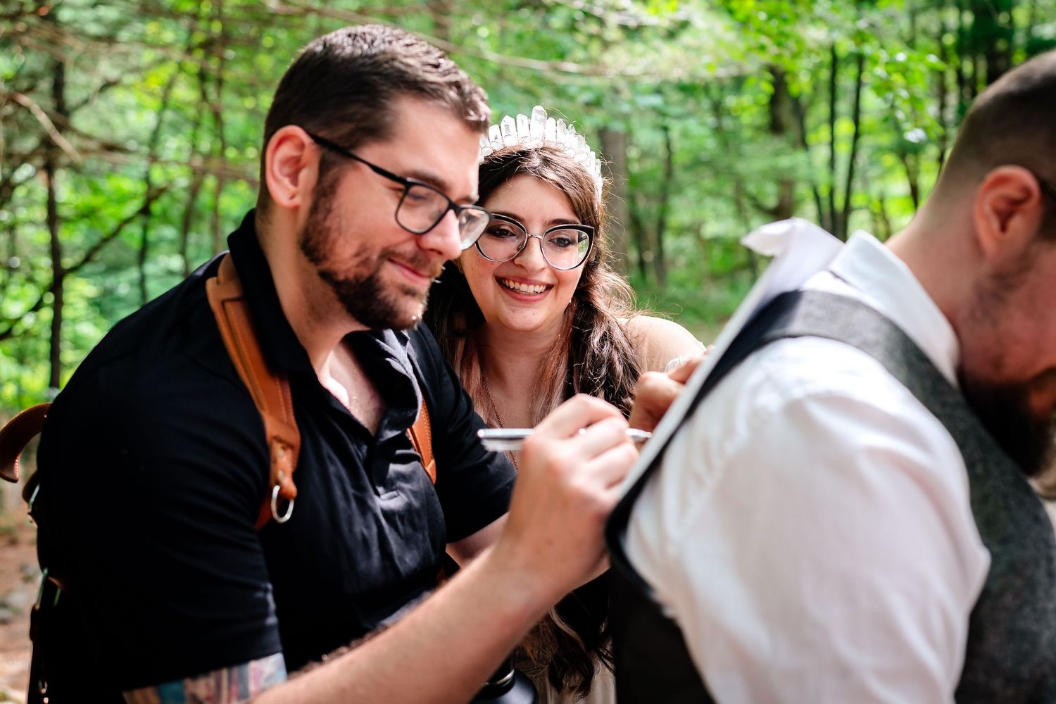 Intimate gathering of wedding party members in a forest setting.
