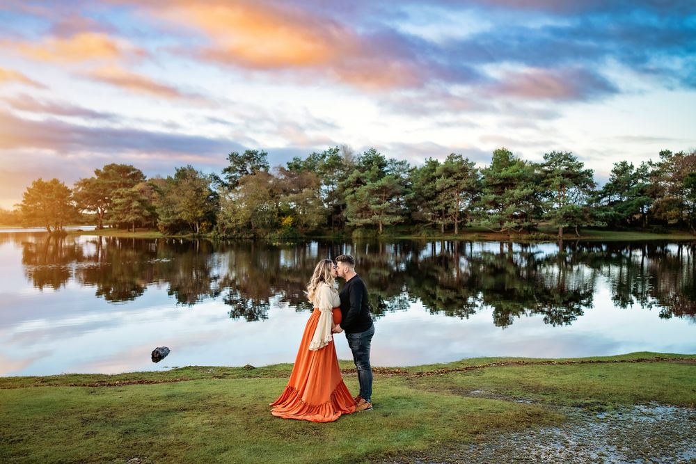 Maternity photo session at Hatchet Pond, New Forest, with trees reflecting in the water.