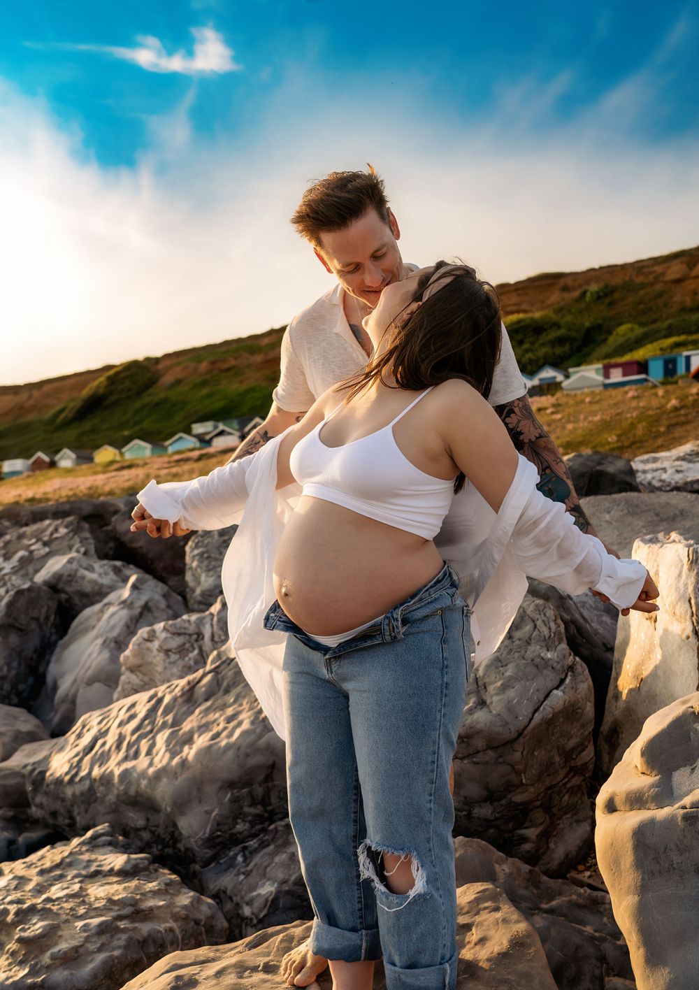 Maternity photo session at Barton on Sea Beach, the couple is playing around and having fun.