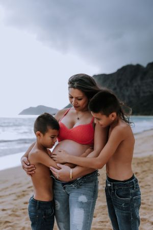 Candid family photography session on a beach showing mother bonding with children.