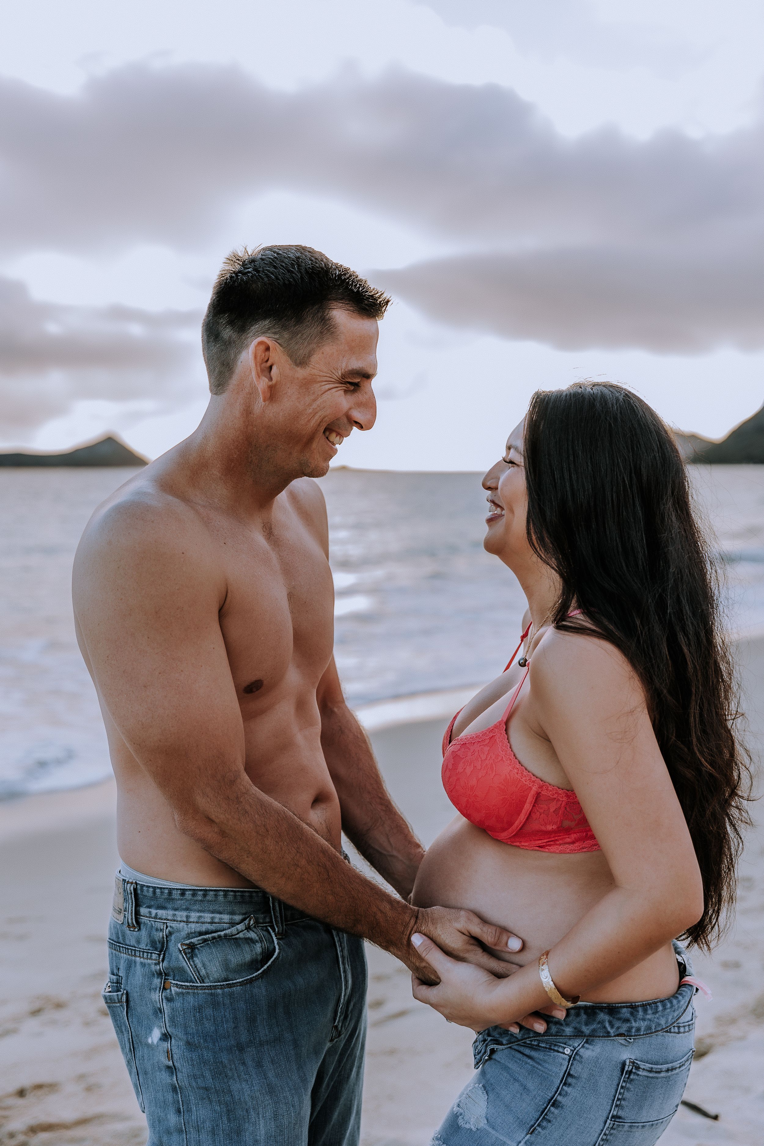 Couple sharing playful and romantic moments together on a cloudy beach.