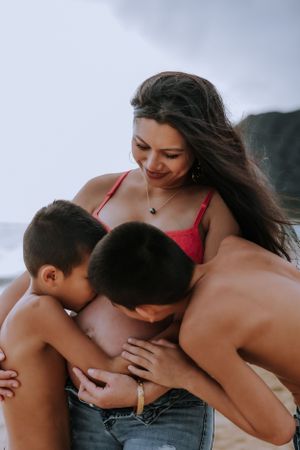 Intimate family beach photoshoot showing tender moments between mother and children.