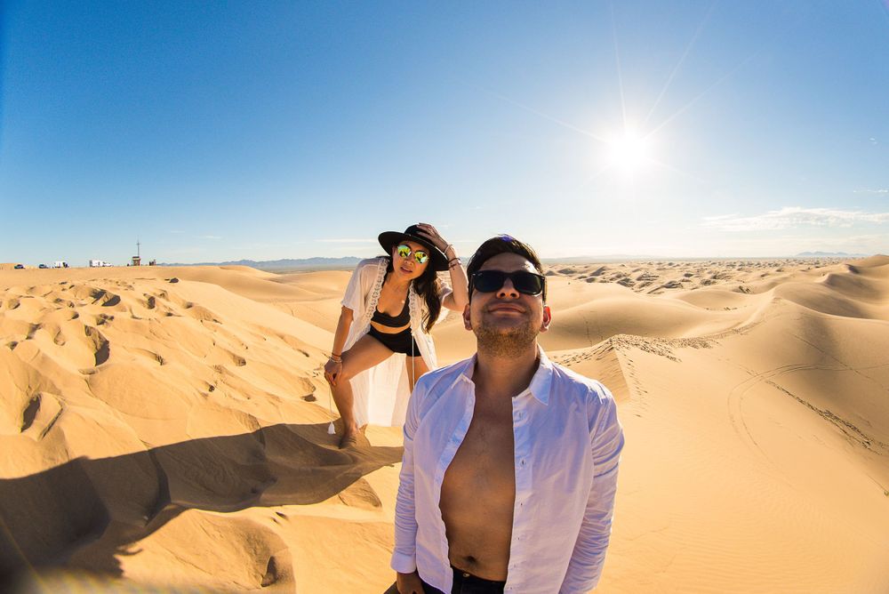 Group enjoying adventures in vast sand dunes under bright blue desert sky.